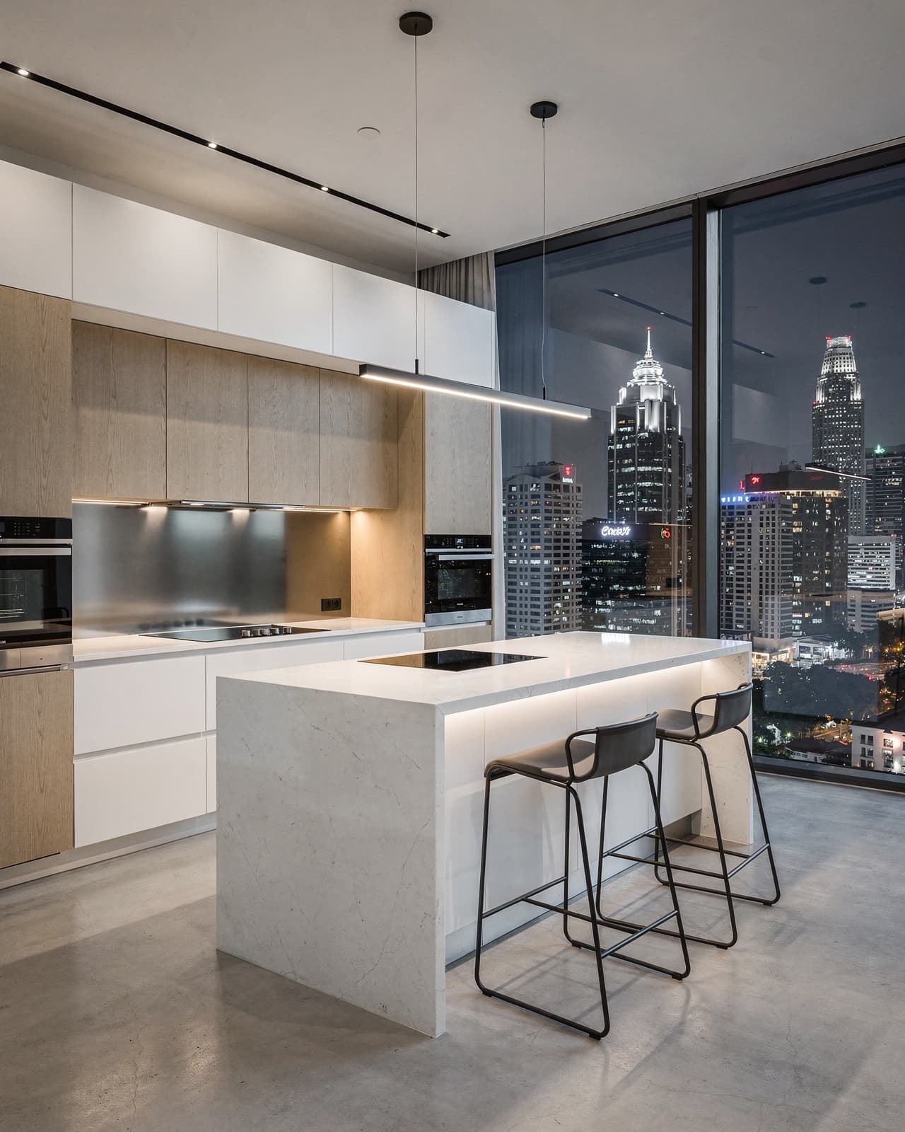A minimalist, open-concept kitchen in a downtown penthouse. Incorporate a massive window wall showcasing the city skyline and use reflective surfaces to amplify the metropolitan glow.