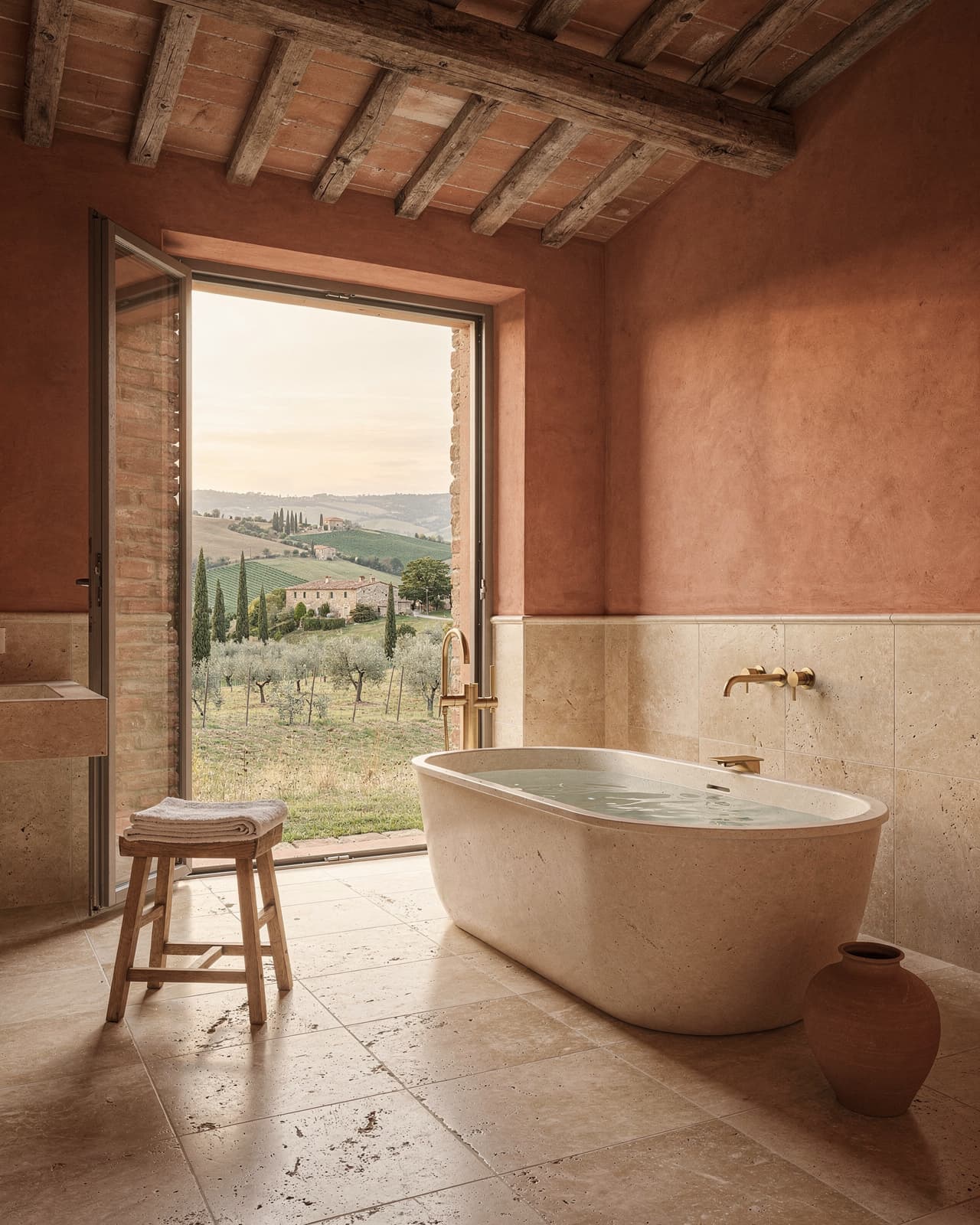 Italian countryside with travertine tiles, warm terracotta accents, and an oversized soaking tub set against a backdrop of rustic wooden beams